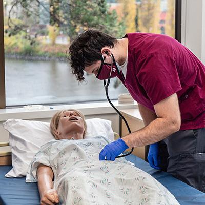 An SPU nursing student completes and exercise with a medical dummy